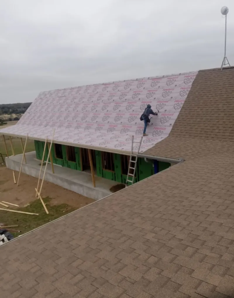 Worker preparing underlayment for a metal roof installation in Sandusky